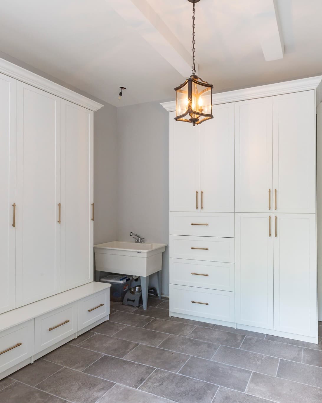 Custom laundry room with white cabinetry and utility sink